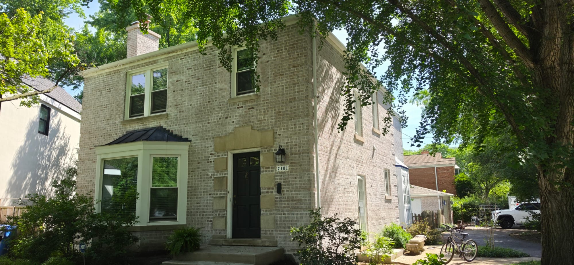 Same two-story brick home after Classico Limewash, finished cream exterior