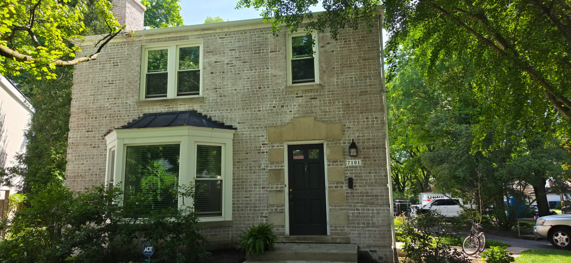 Two-story brick home before limewash, unpainted tan brick