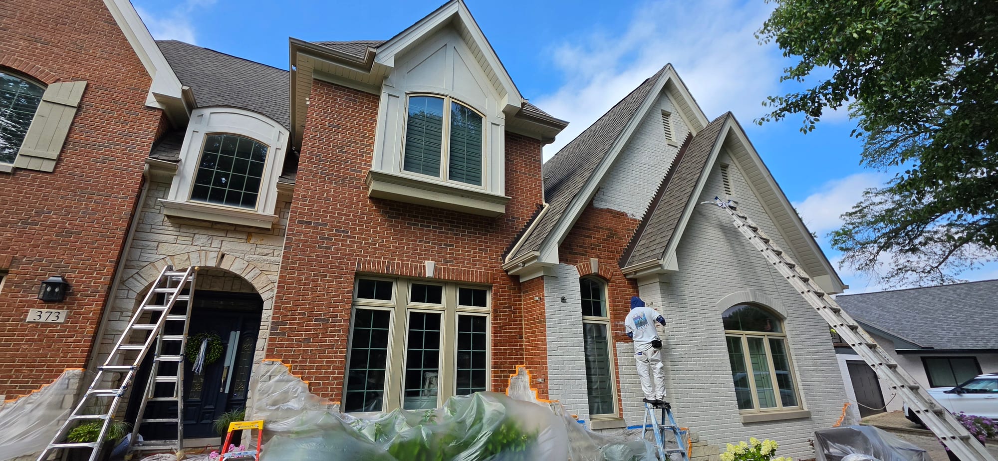 Brick exterior mid-application showing original red brick alongside finished white limewash on the same wall