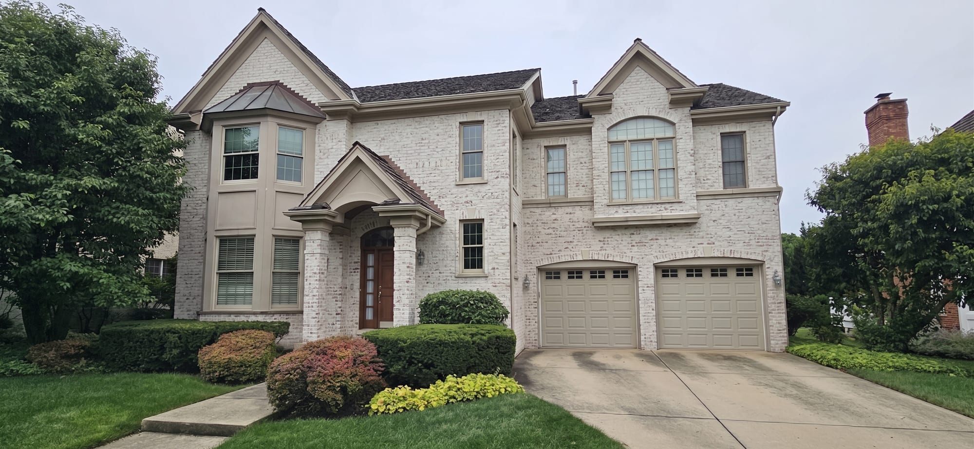 Limewash finish on a cream brick two-story colonial exterior.